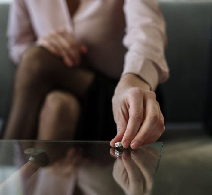 A person sitting on the couch with their hand on a glass table.